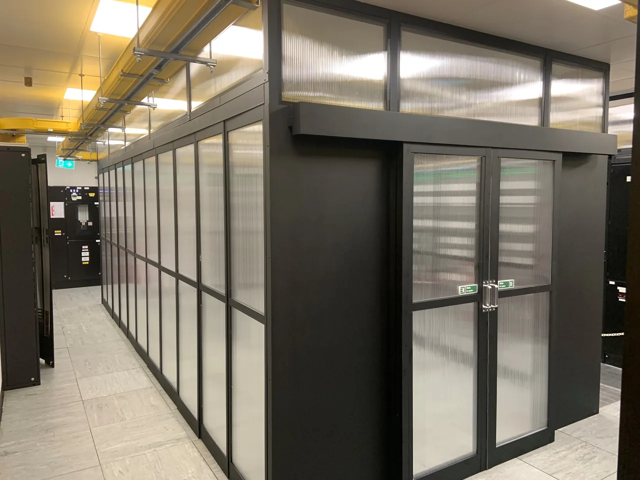 Black framed containment enclosure with translucent panels and a double entrance
