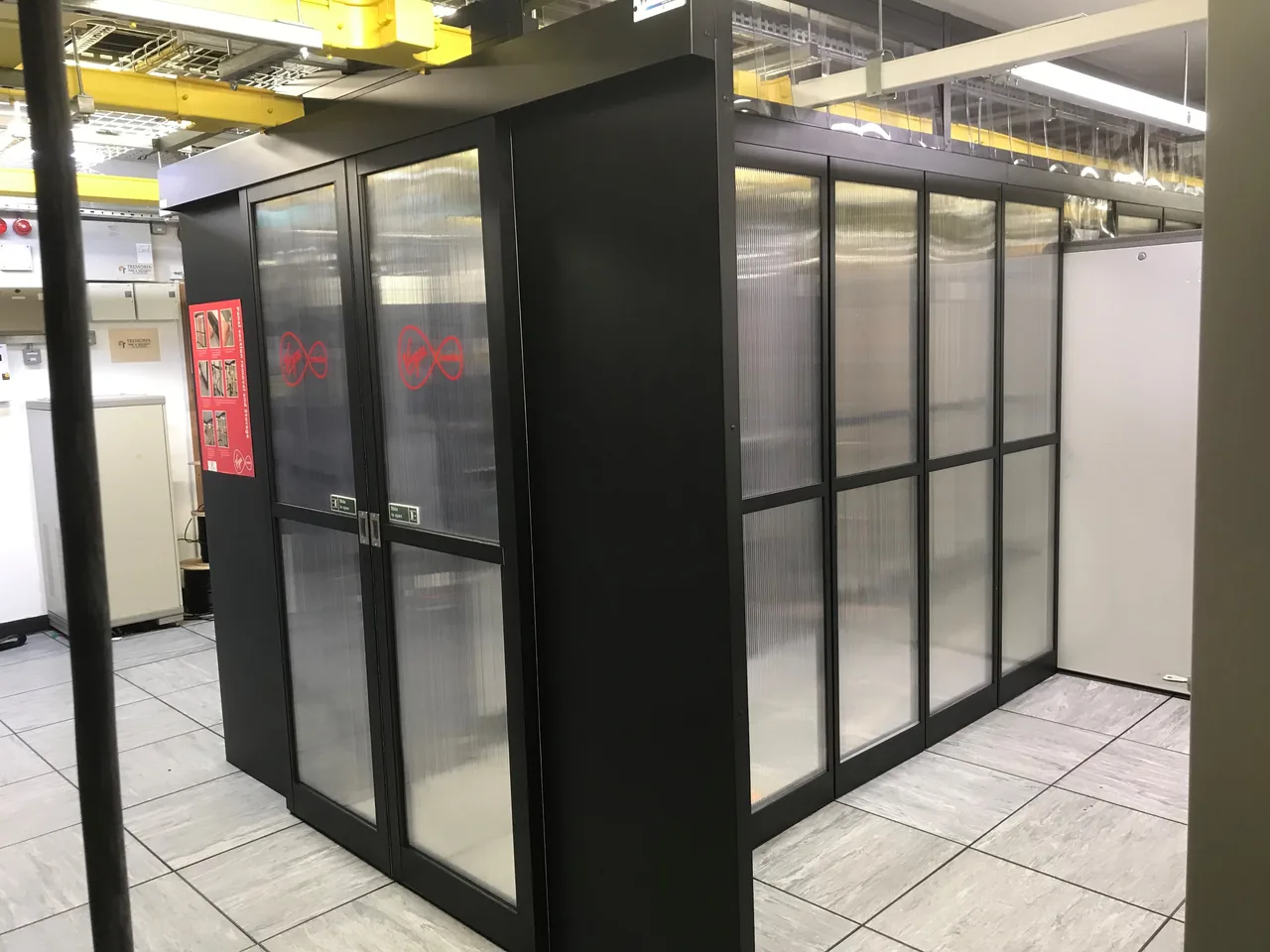 Black framed containment panels and a doorway alongside equipment racks
