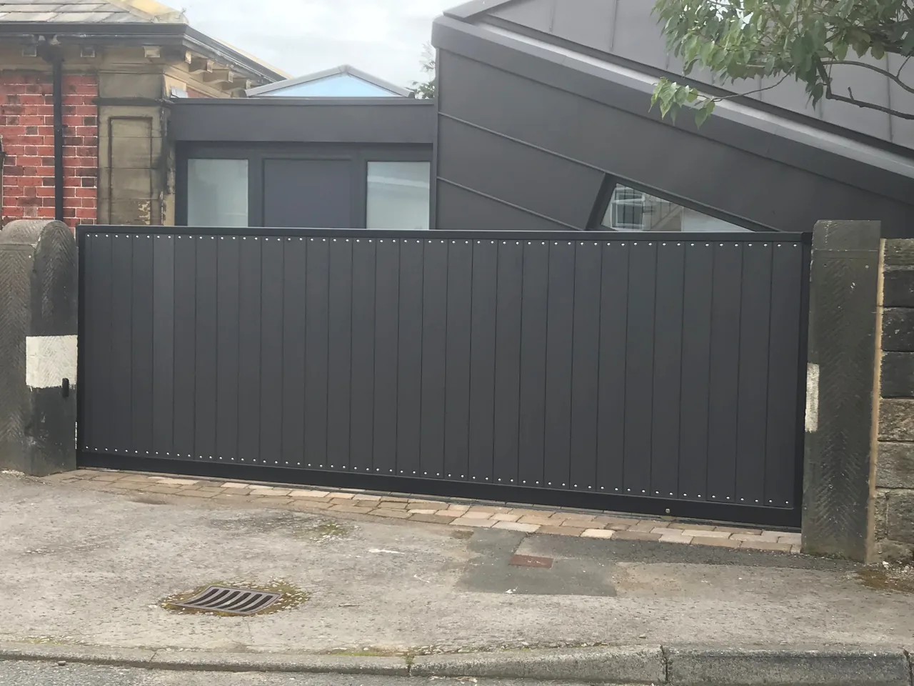 Wide dark sliding gate across a driveway entrance