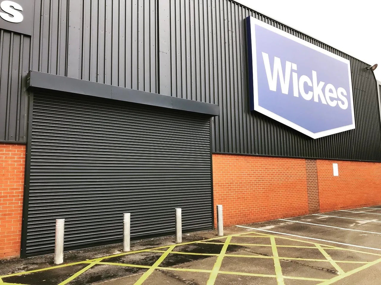 Dark roller shutter closing a commercial entrance beneath black cladding