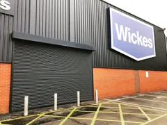Dark roller shutter closing a commercial entrance beneath black cladding