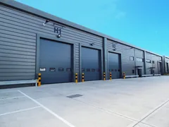 Row of grey sectional loading bay doors on a clad industrial building