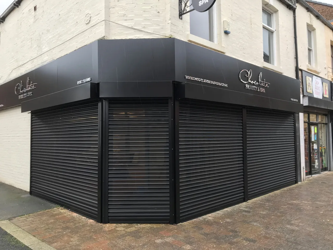 Black shutters covering both sides of a corner shopfront