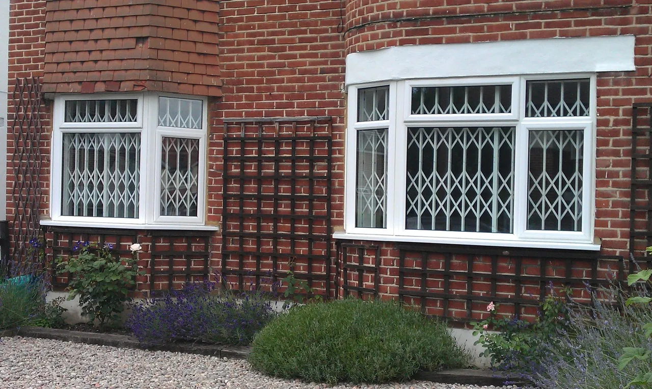 White retractable security grilles behind windows in a brick building