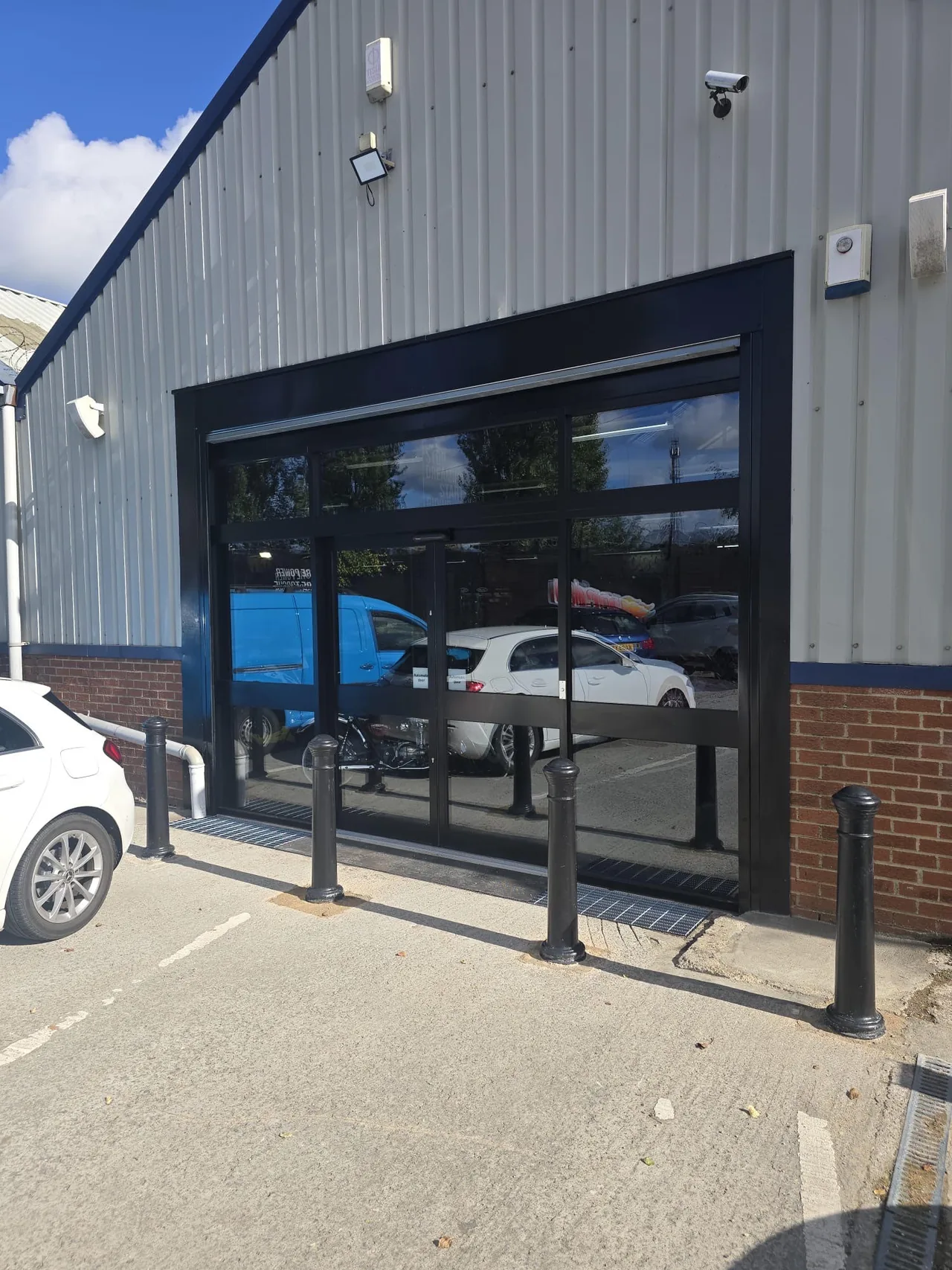 Full-height black-framed glazed entrance with the roller shutter raised at Jordan’s Bikes.